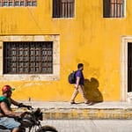 moto et passant devant une façade jaune au mexique
