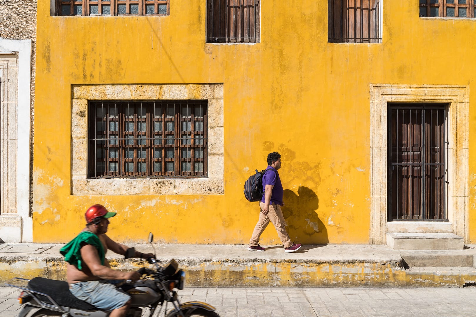 moto et passant devant une façade jaune au mexique